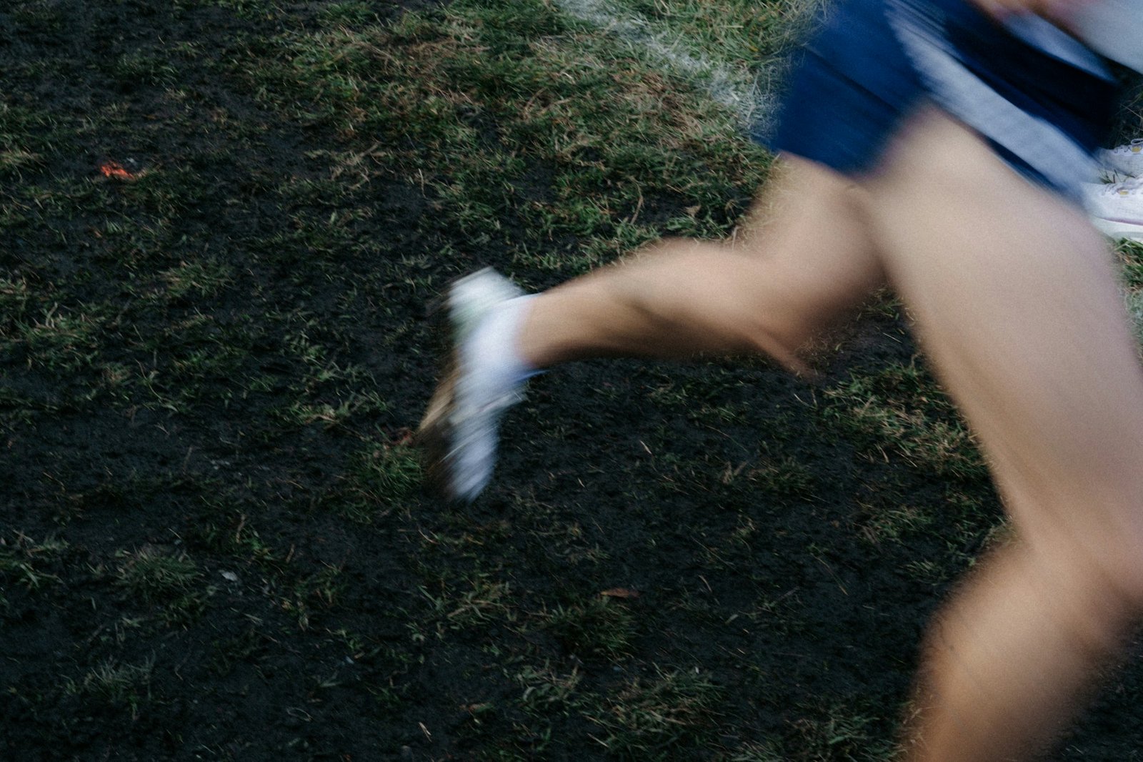 A runner's legs in motion on grassy terrain.