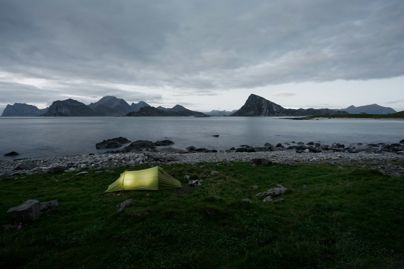 Wild-camp tent under a Norwegian fjord cliff.
