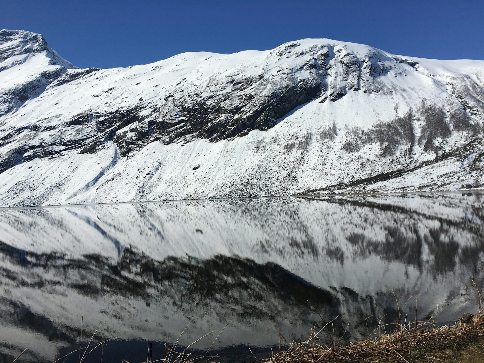 A snow covered mountain with a lake in the foreground