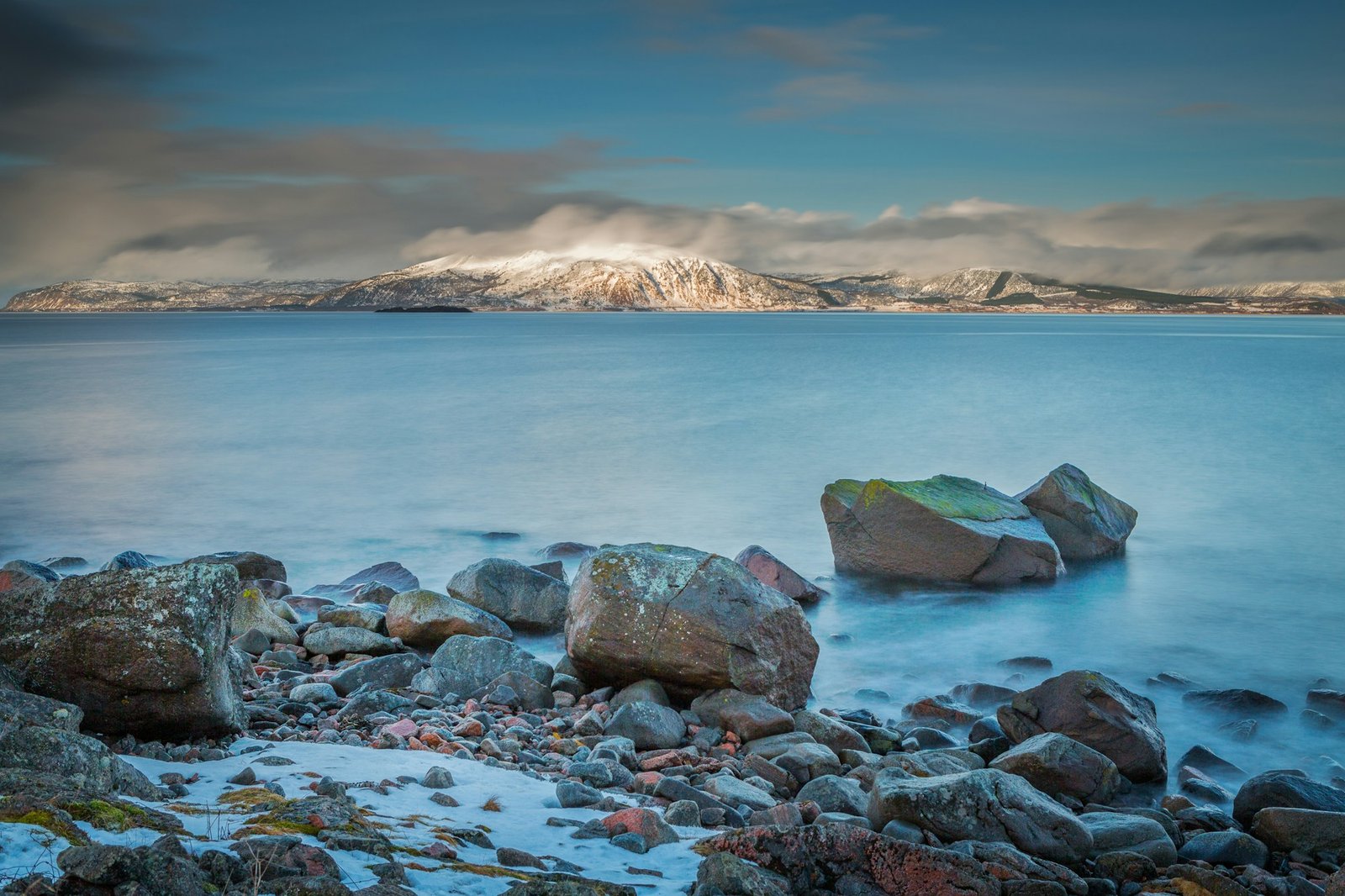 gray and brown rocks near body of water under cloudy sky during daytime