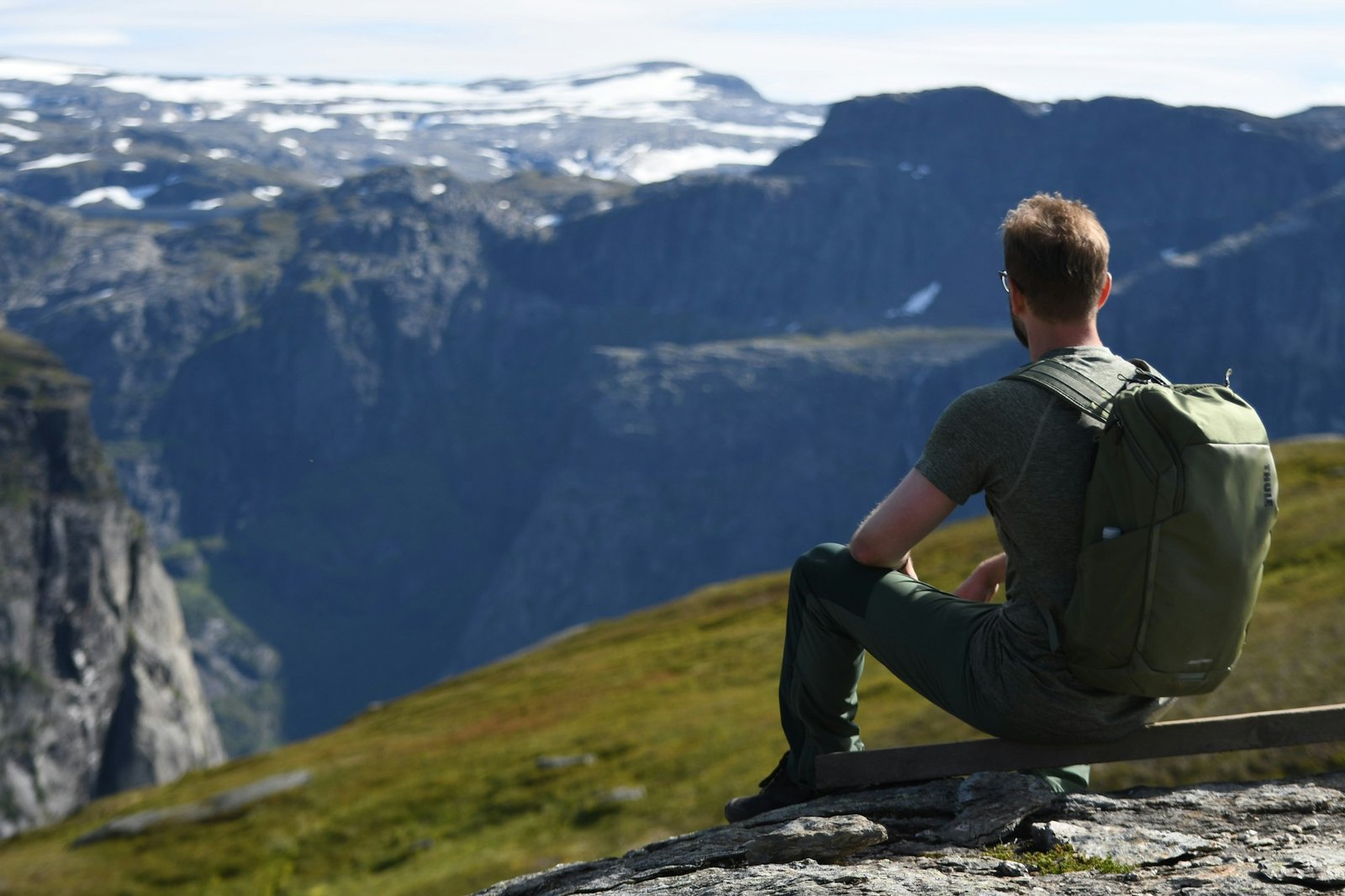 a man sitting on top of a mountain with a backpack