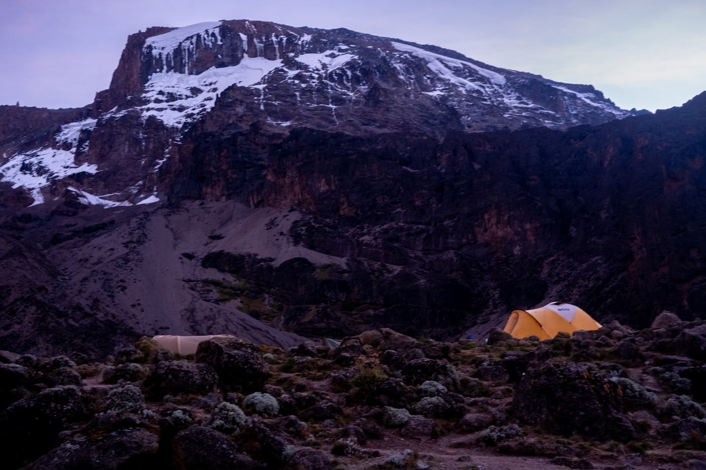 Porters and climbers walking through one of Kilimanjaro's high camps.