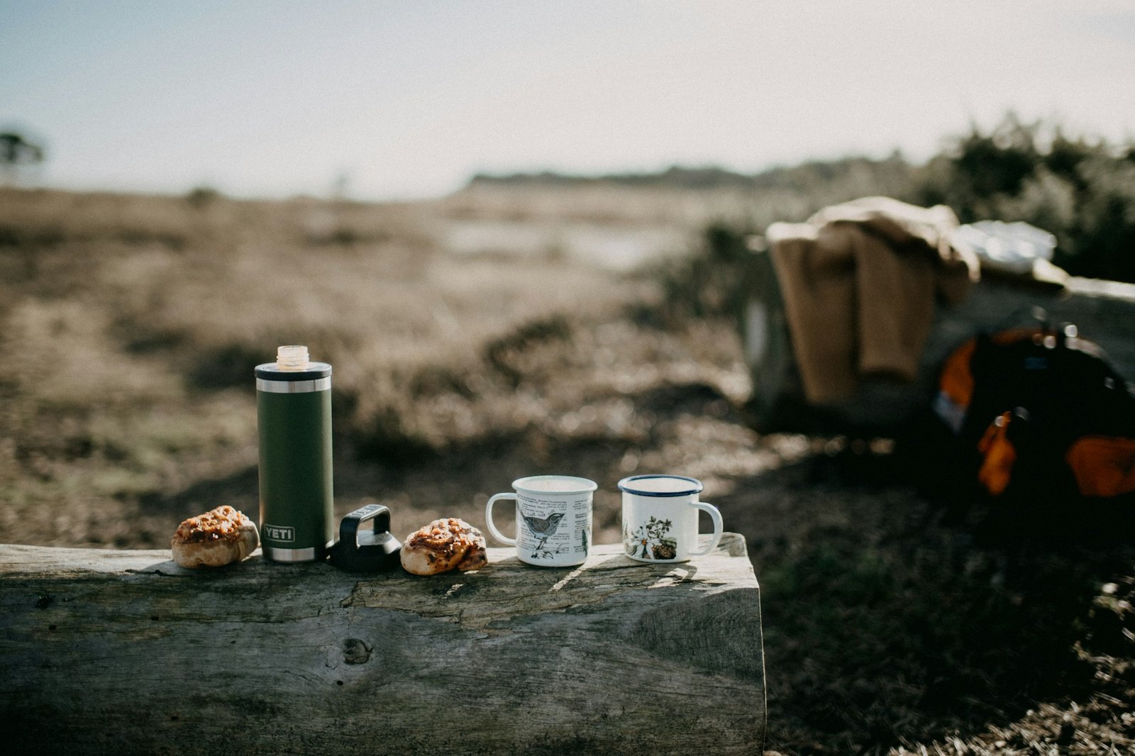 A coffee mug on a wooden surface in soft outdoor light.