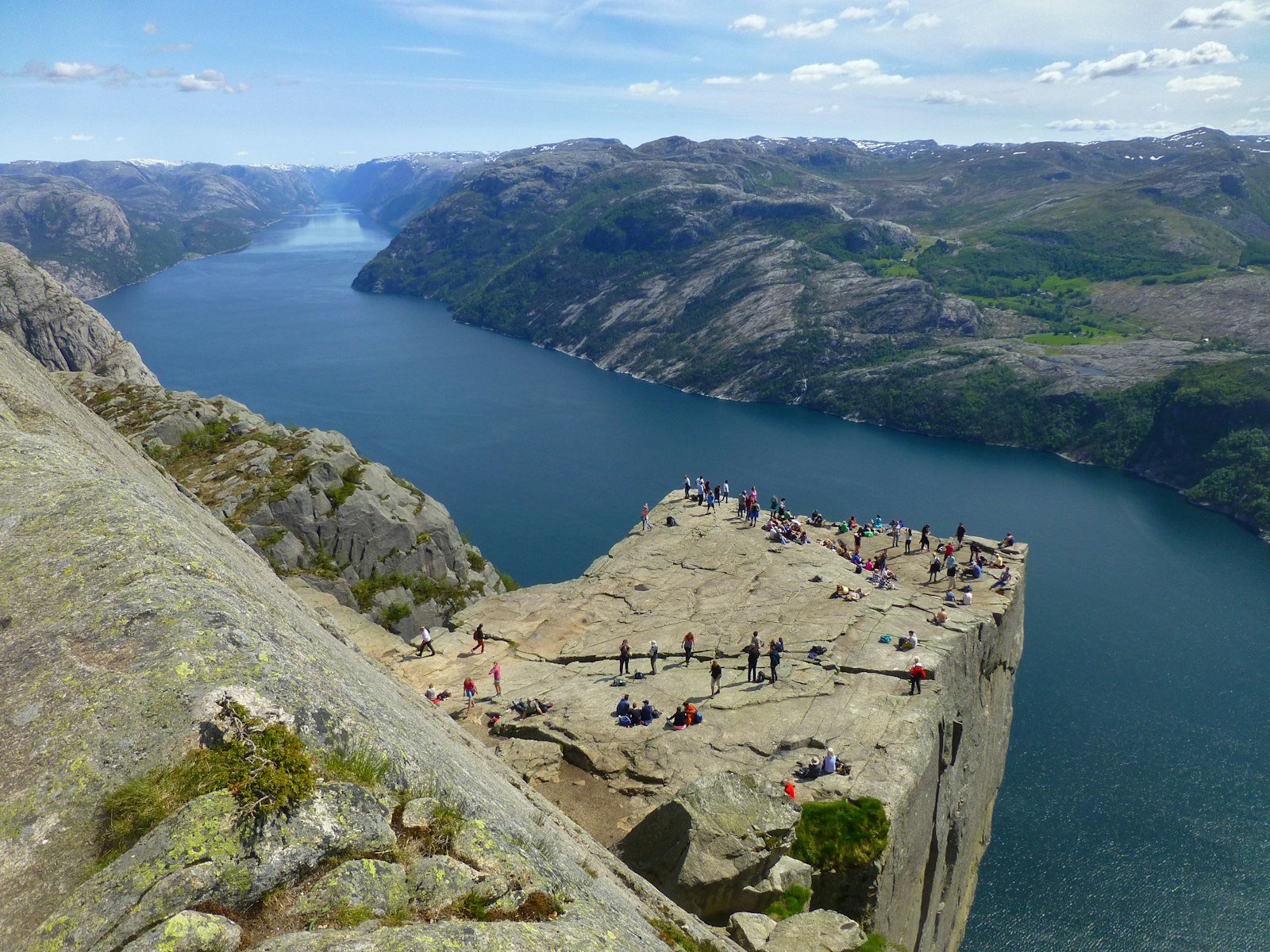 A group of hikers standing on the edge of Preikestolen with the Lysefjord below.